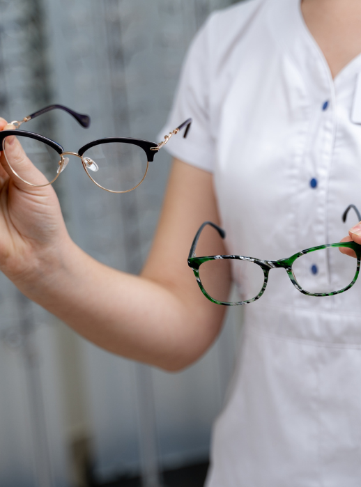 optician holding two pairs of glasses