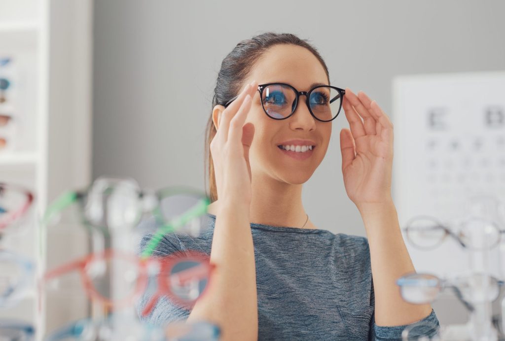 Young smiling woman choosing her new glasses